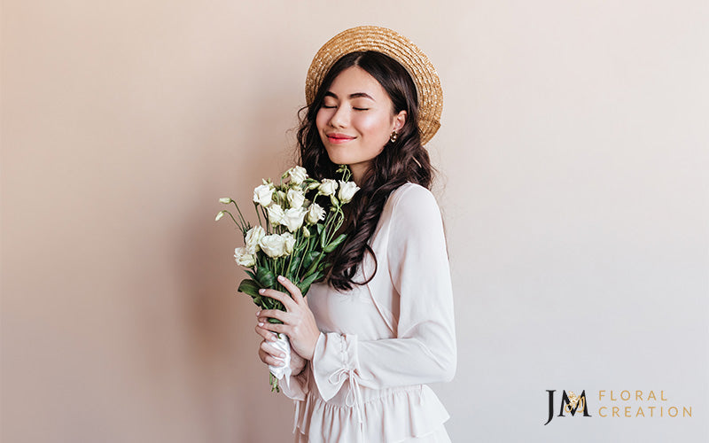 A person smiling while holding a flower bouquet